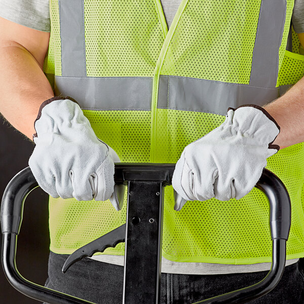 A person wearing Cordova grain cowhide leather driver's gloves and a safety vest holding a hand truck.