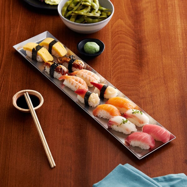 A rectangular stainless steel plate with sushi on it.