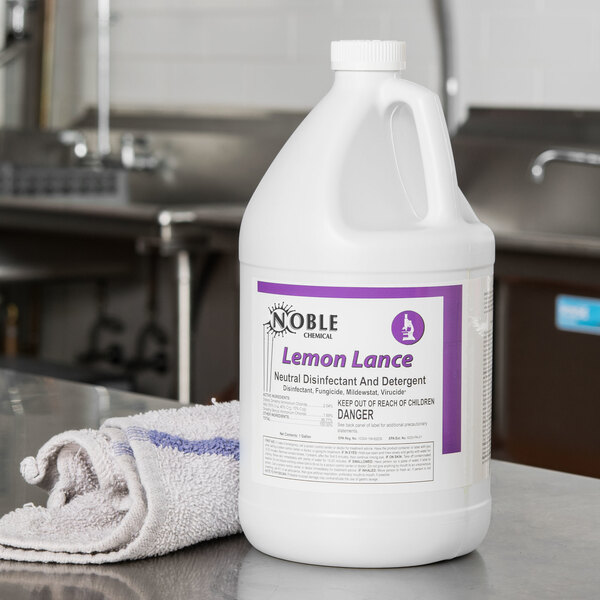 A white jug of Noble Chemical Lemon Lance sitting on a counter with a white towel.