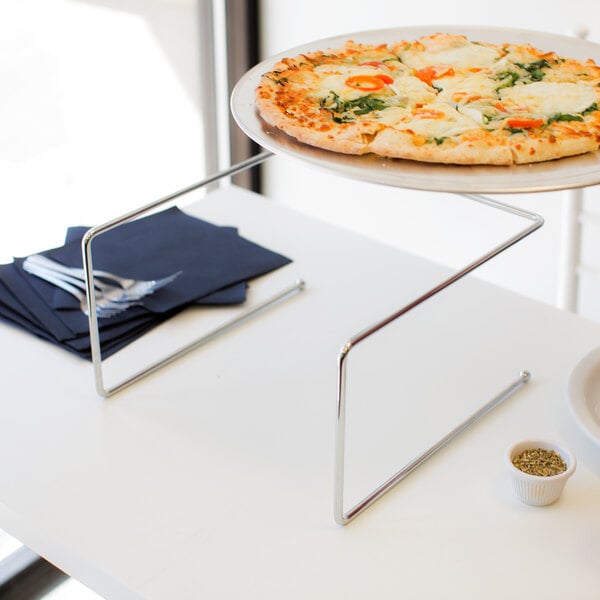 A pizza on a chrome metal pizza stand.