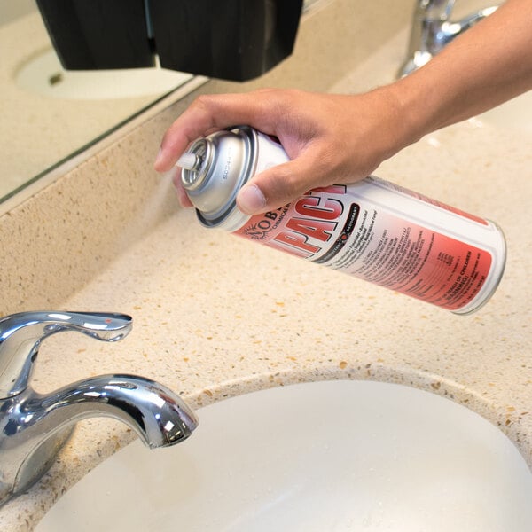 A hand spraying Noble Chemical Impact Disinfectant on a sink.