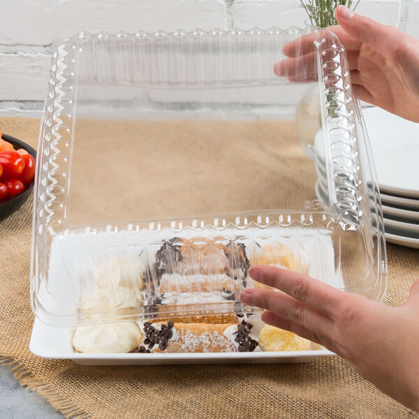 A hand holding a Fineline clear plastic container with food inside.