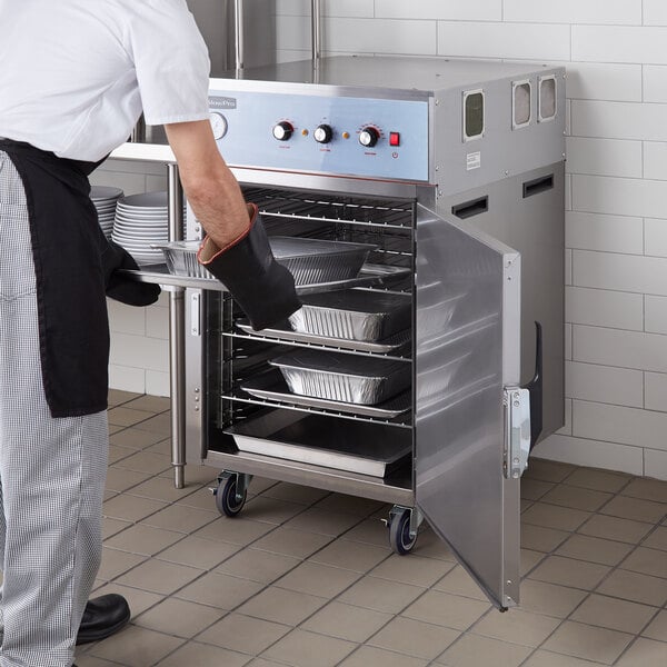 A man putting food into a Cooking Performance Group SlowPro Cook and Hold Oven.