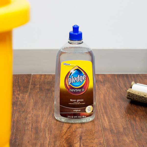 A bottle of SC Johnson Pledge Multi-Surface Floor Care Finish on a wood surface.