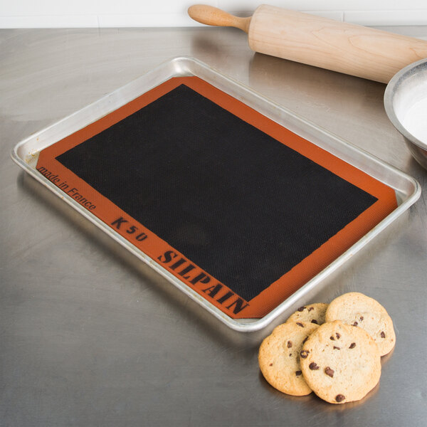 A baking mat on a baking tray with cookies.