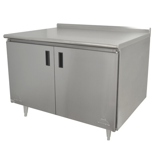 A stainless steel Advance Tabco work table with an enclosed cabinet and hinged doors.