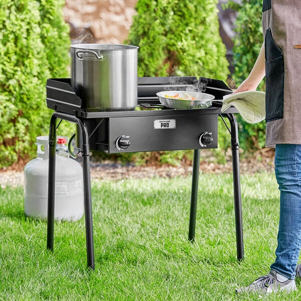 A woman cooking food on a Backyard Pro double burner outdoor range.