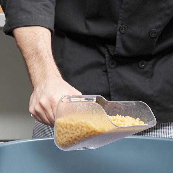 A person holding a Rubbermaid Bouncer Scoop filled with pasta over a bowl of noodles.