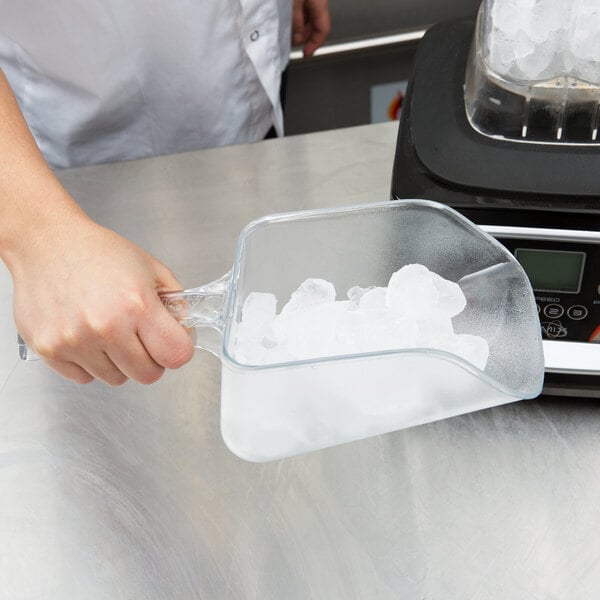 A person holding a Rubbermaid clear plastic utility scoop full of ice.