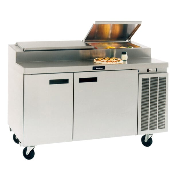 A Delfield stainless steel refrigerated pizza prep table with pizza on it.
