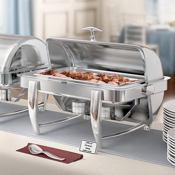 A buffet table with Acopa stainless steel chafers full of food and silverware.