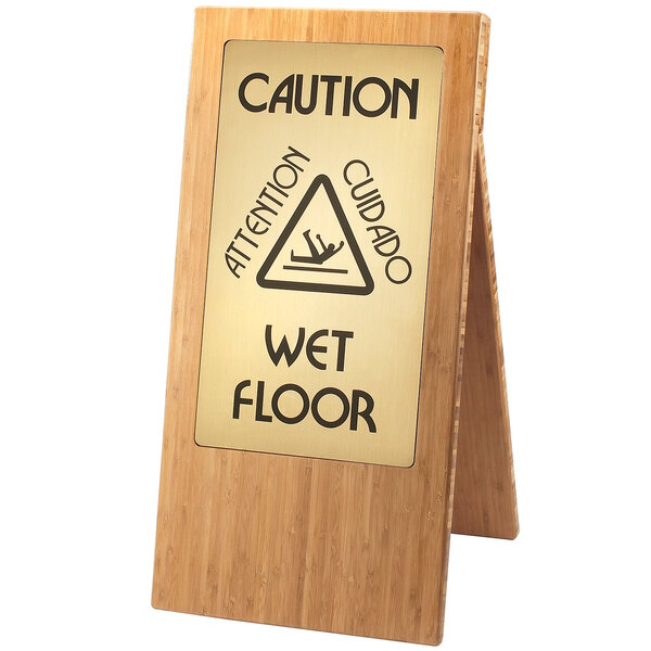 A Cal-Mil bamboo wet floor sign with a triangular sign on a wooden stand.