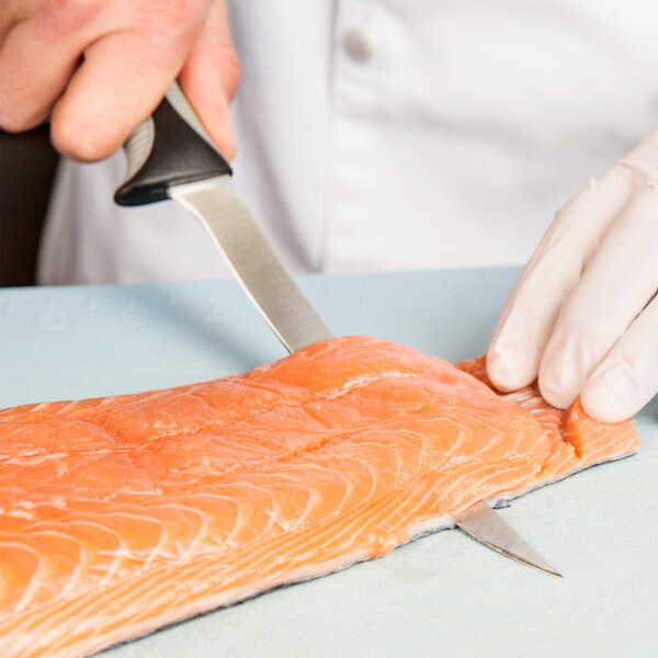 A person in gloves using a Dexter-Russell V-Lo flexible boning knife to cut a piece of salmon.