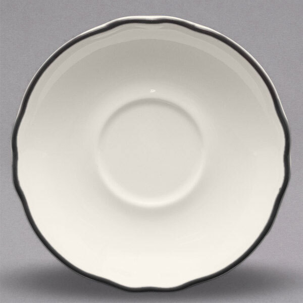 A white saucer with a black scalloped rim.
