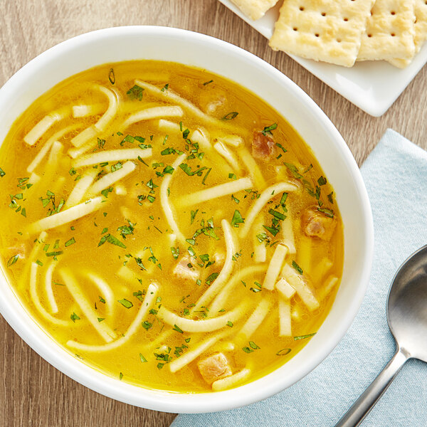 A bowl of Campbell's Chicken Noodle Soup with noodles and a spoon.