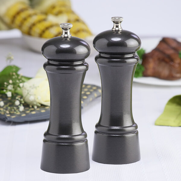 A black metal Chef Specialties pepper mill and salt mill set on a table.