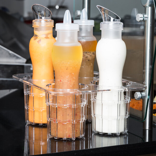 A group of GET polycarbonate salad dressing and juice bottles on a counter.