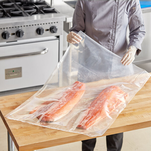 A woman in a chef's uniform vacuum sealing fish in a VacPak-It vacuum packaging pouch.