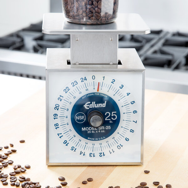 An Edlund white and blue mechanical portion scale with coffee beans on it.