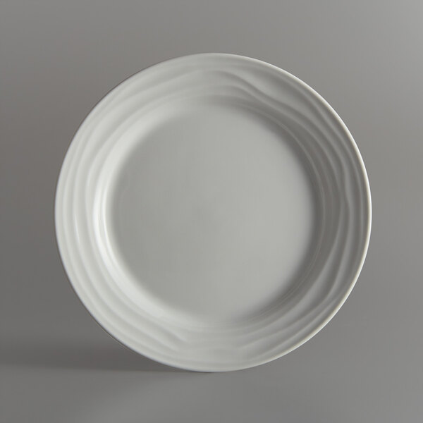 A close-up of a Tuxton TuxTrendz Sandbar bright white china plate with swirls on it.