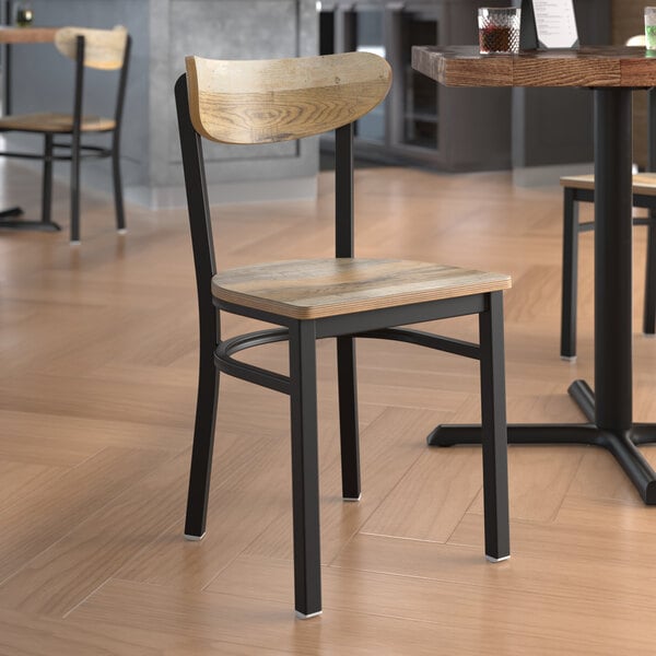 A Lancaster Table & Seating Boomerang chair with a driftwood seat and back on a table in a restaurant.