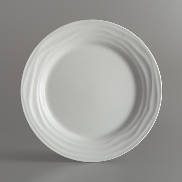 A close-up of a Tuxton TuxTrendz Sandbar bright white china plate with swirls.