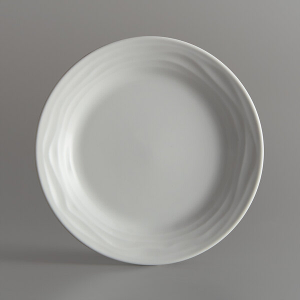 A Tuxton TuxTrendz Sandbar bright white china plate with a thin wavy rim.