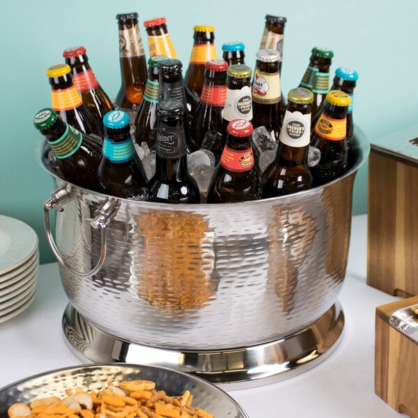 A Tablecraft stainless steel beverage tub filled with beer bottles on a table.