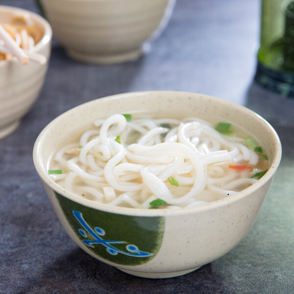 A Japanese GET melamine bowl filled with noodle soup with green and white noodles.