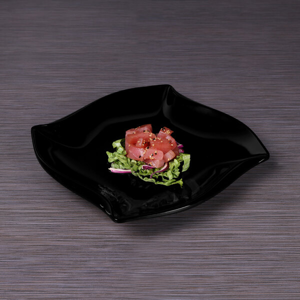 A black Elite Global Solutions irregular square melamine plate with raw tuna and lettuce on it.