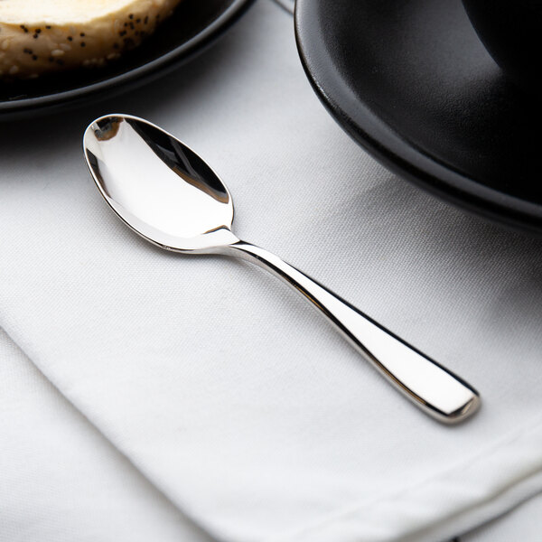A Oneida Perimeter stainless steel demitasse spoon on a table.