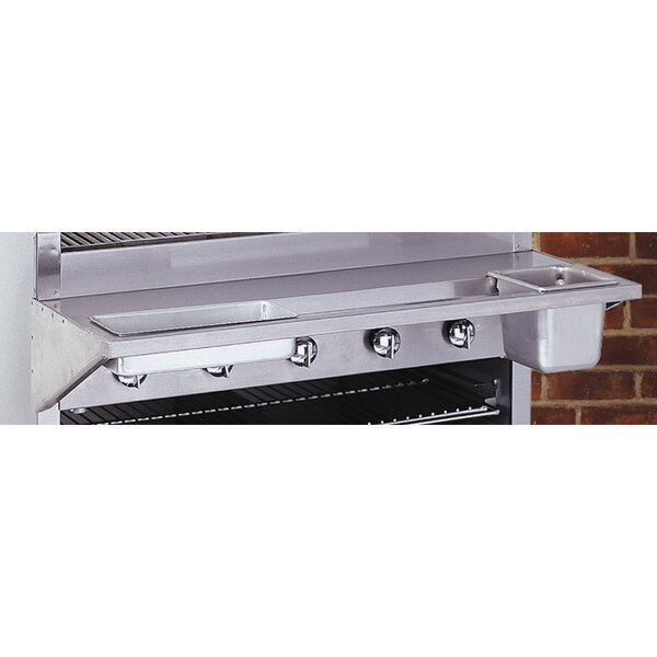 A stainless steel Bakers Pride work deck with condiment rail on a grill.