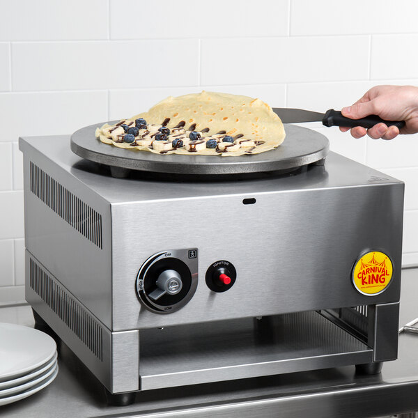 A person using a Carnival King liquid propane crepe maker to cook a crepe.