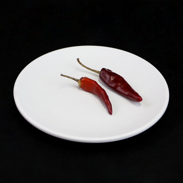 An Elite Global Solutions off white melamine plate with a couple of red peppers on it.