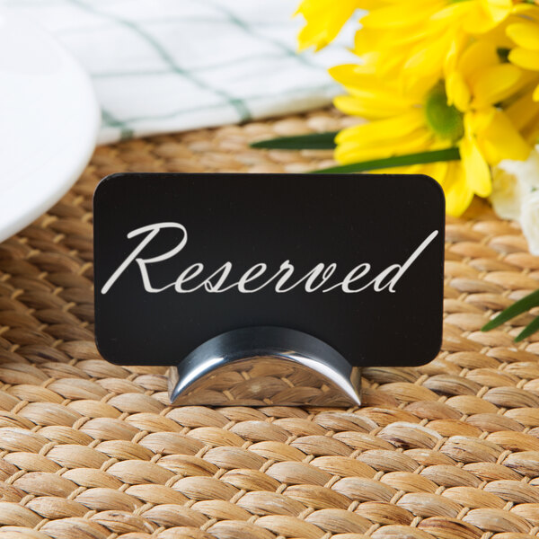 A Tablecraft stainless steel semicircle card holder with a reserved sign on a table.
