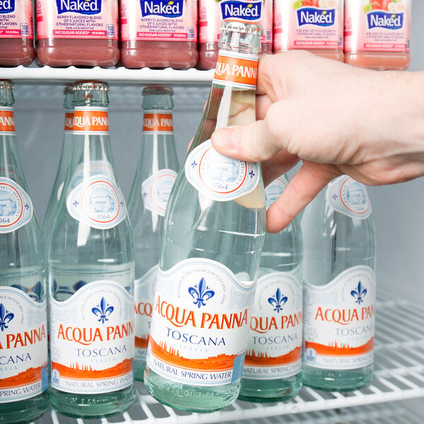 A person holding a bottle of Acqua Panna Natural Spring Water.
