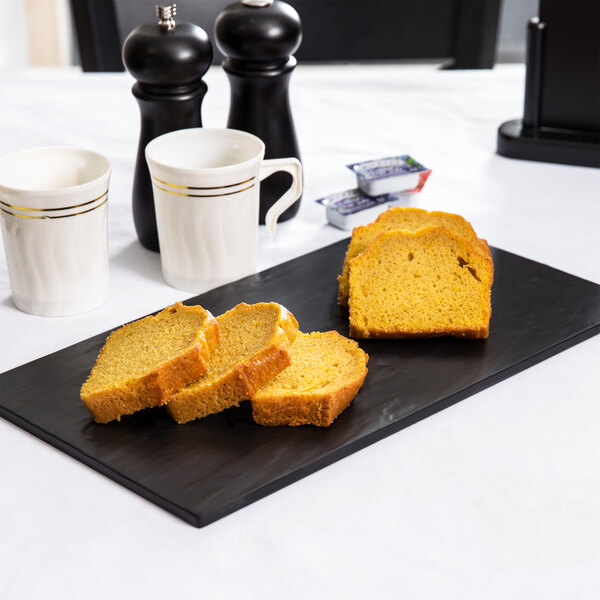 A black American Metalcraft melamine platter with slices of bread, a loaf of bread, and salt and pepper shakers on it.