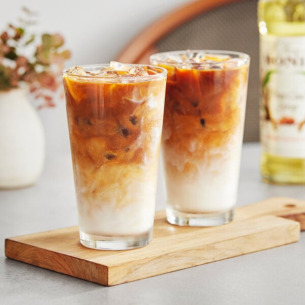 Two glasses of Monin pure cane syrup iced coffee on a wooden tray.