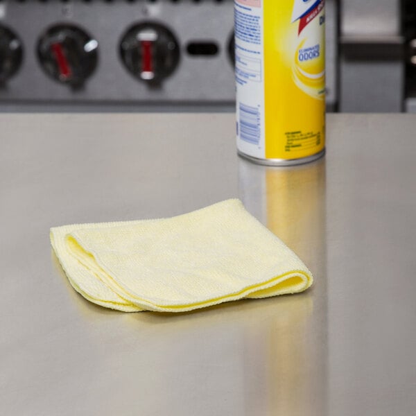 A yellow Rubbermaid microfiber cloth on a counter next to a can of cleaning agent.