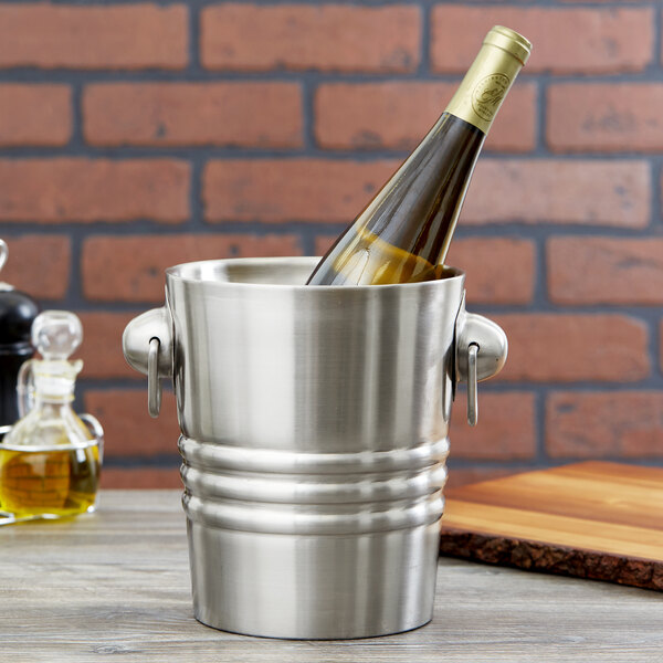 A Vollrath silver wine bucket with a bottle of wine in it.