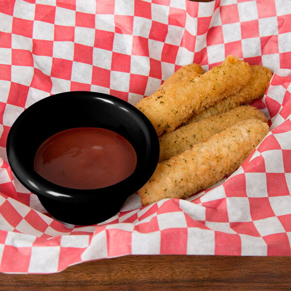 A black Thunder Group ramekin filled with red sauce next to fried mozzarella sticks.