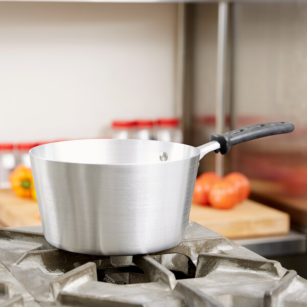 The black silicone handle of a Vollrath Wear-Ever sauce pan sitting on a stove.