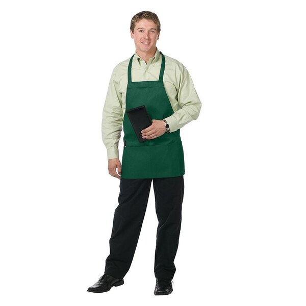 A man wearing a hunter green Chef Revival bib apron with 3 pockets in a professional kitchen.