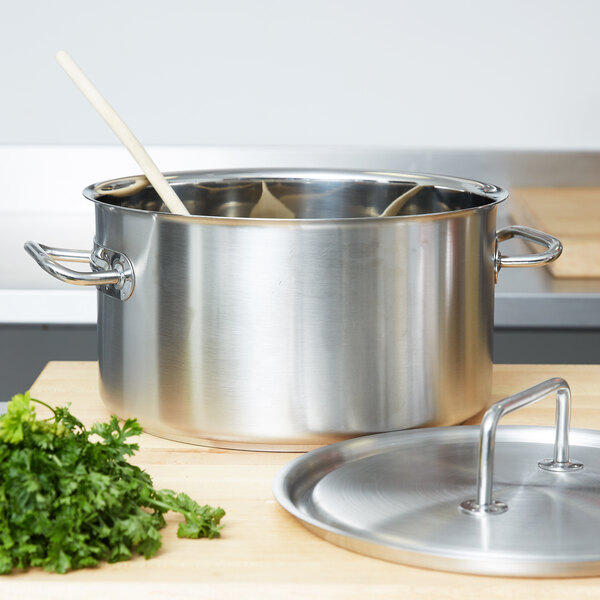 A Vollrath stainless steel sauce pot with a wooden spoon in it.