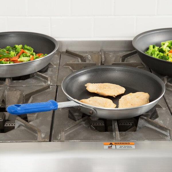 Two Vollrath Wear-Ever non-stick fry pans cooking meat and vegetables.