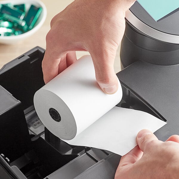 A person holding a Point Plus thermal cash register paper roll.