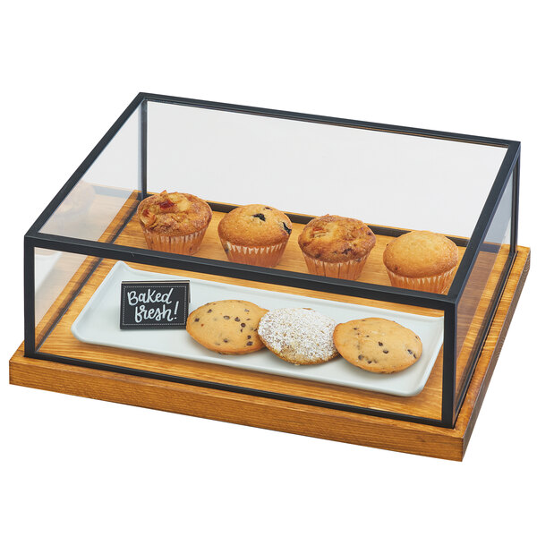 A Cal-Mil Madera presentation case on a counter with muffins and cookies inside.