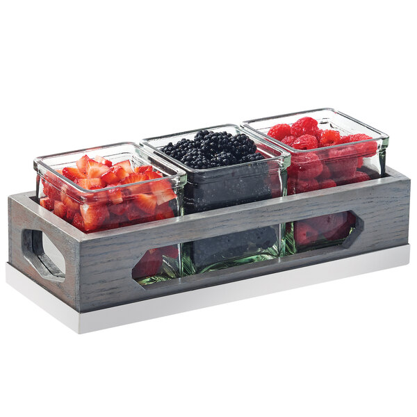 A Cal-Mil wood organizer with three glass jars filled with different berries.