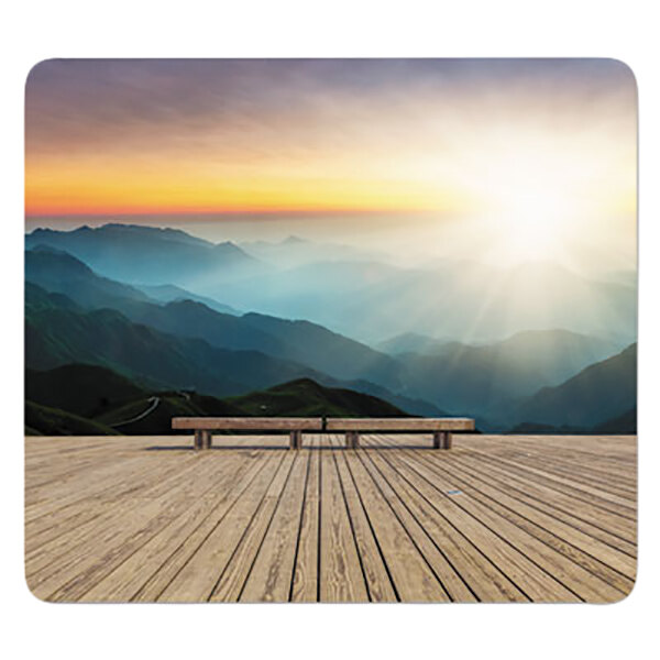 A Fellowes mouse pad on a wooden table on a wooden deck overlooking a mountain range at sunset.