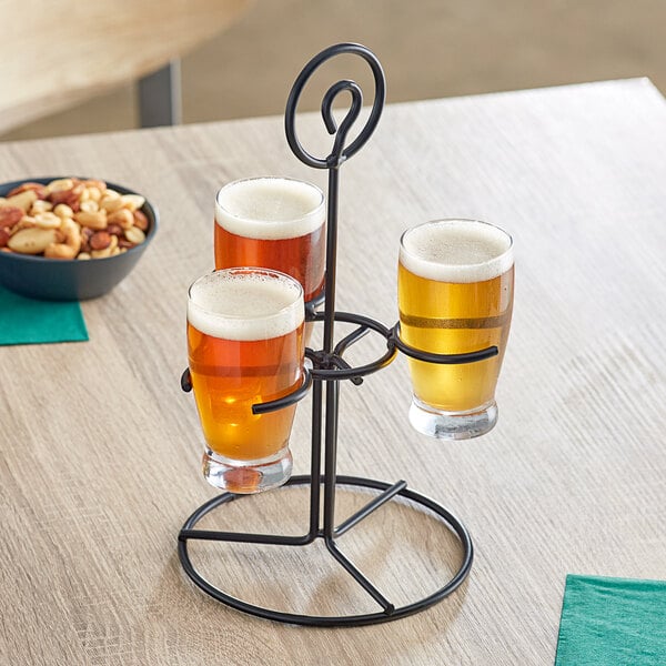 An Acopa metal stand holding three Barbary beer glasses filled with beer.